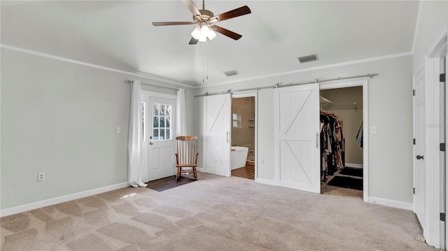 unfurnished bedroom with ensuite bathroom, a spacious closet, ceiling fan, a barn door, and a closet