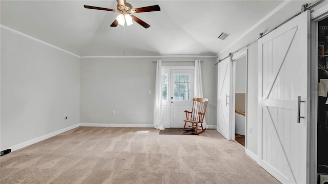 interior space with ceiling fan, ornamental molding, a barn door, and light colored carpet