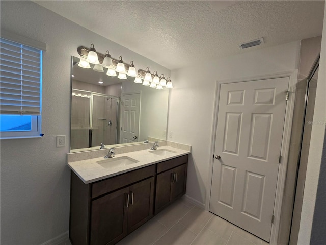 bathroom with tile patterned floors, a shower with shower door, a textured ceiling, and vanity