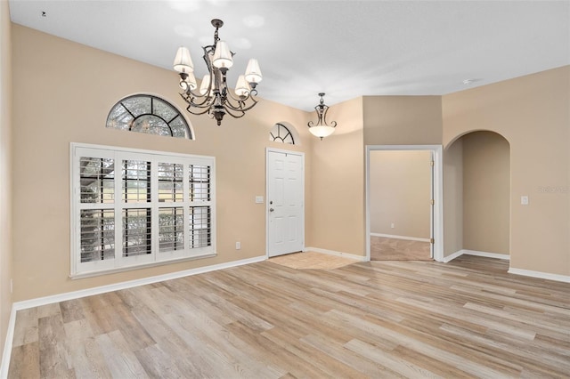 spare room featuring a chandelier and light wood-type flooring