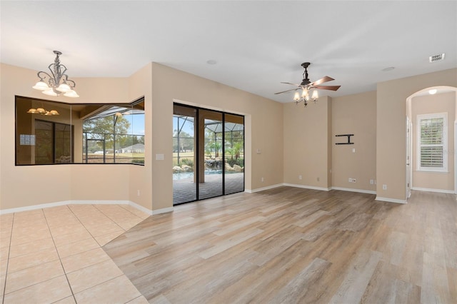 unfurnished room featuring ceiling fan with notable chandelier and light hardwood / wood-style floors