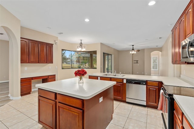 kitchen featuring sink, light tile patterned floors, appliances with stainless steel finishes, decorative light fixtures, and kitchen peninsula