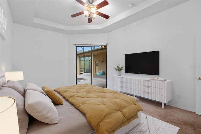 bedroom with ceiling fan, access to exterior, a raised ceiling, and carpet