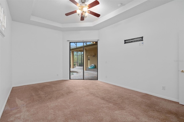 spare room featuring ceiling fan, a raised ceiling, and carpet floors