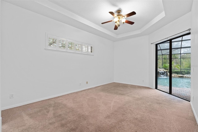 unfurnished room featuring ceiling fan, a raised ceiling, and carpet