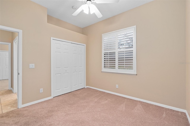 unfurnished bedroom with ceiling fan, light carpet, and a closet