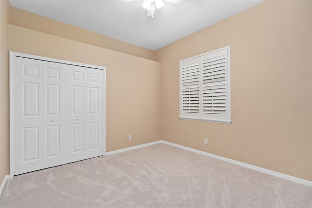 unfurnished bedroom featuring light carpet, ceiling fan, and a closet