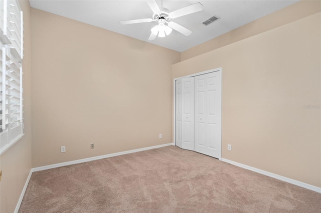 unfurnished bedroom with light colored carpet, a closet, and ceiling fan