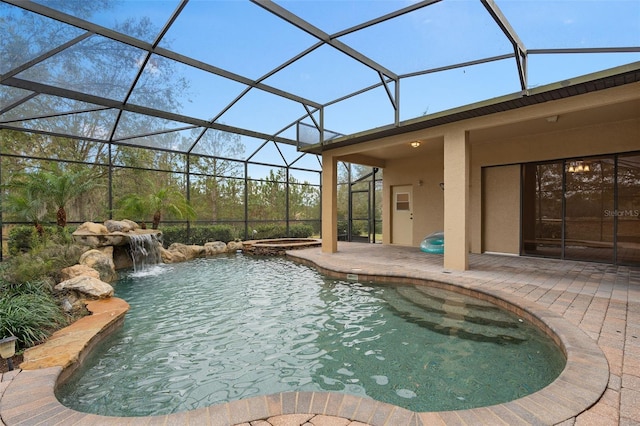 view of swimming pool featuring an in ground hot tub, pool water feature, a patio area, and glass enclosure