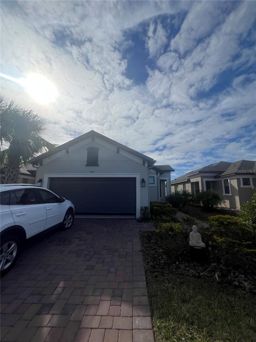 view of home's exterior with an attached garage, decorative driveway, and stucco siding