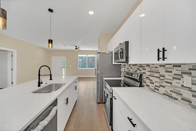 kitchen with pendant lighting, sink, white cabinetry, and appliances with stainless steel finishes