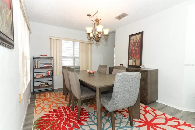 dining room featuring a chandelier, a textured ceiling, and dark hardwood / wood-style flooring