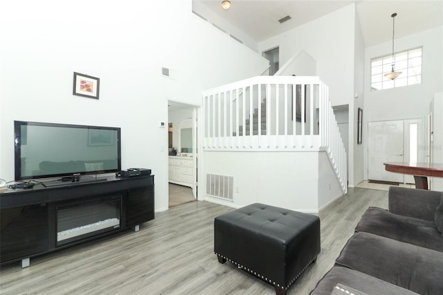 living room with a towering ceiling and light hardwood / wood-style flooring