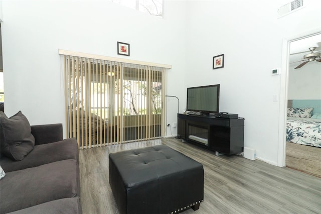 living room featuring hardwood / wood-style flooring, ceiling fan, and a high ceiling