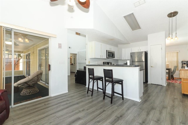 kitchen with a kitchen bar, white cabinetry, kitchen peninsula, ceiling fan, and stainless steel appliances