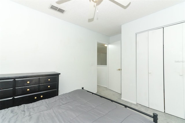 unfurnished bedroom featuring ceiling fan, a closet, light carpet, and a textured ceiling