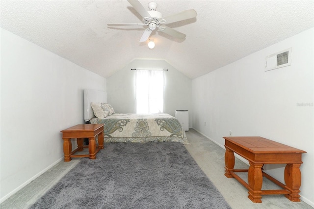 bedroom with ceiling fan, lofted ceiling, light colored carpet, and a textured ceiling