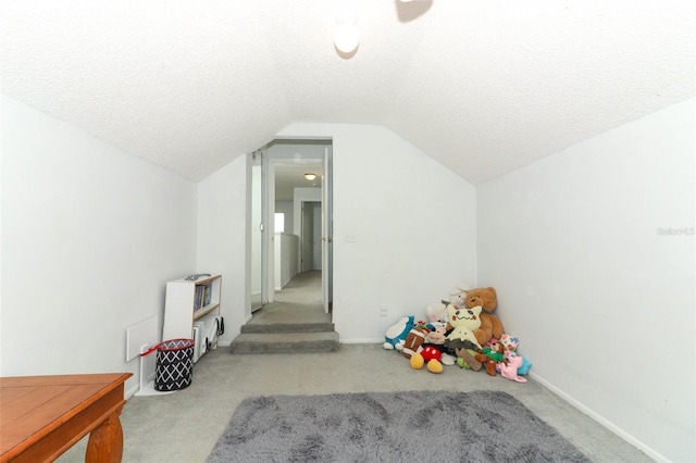 game room with vaulted ceiling, light colored carpet, and a textured ceiling