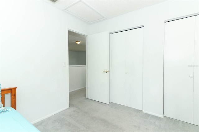 unfurnished bedroom featuring light colored carpet and multiple closets