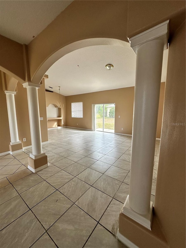 unfurnished living room with ornate columns and light tile patterned floors