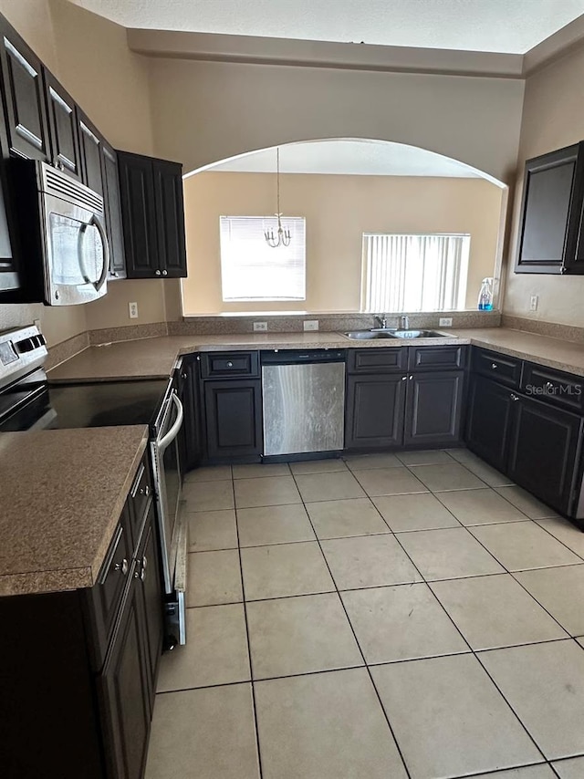 kitchen with light tile patterned flooring, sink, an inviting chandelier, decorative light fixtures, and appliances with stainless steel finishes