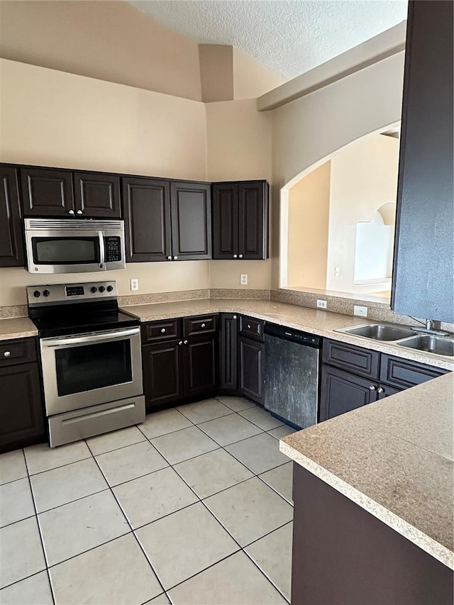 kitchen featuring light tile patterned flooring, appliances with stainless steel finishes, sink, and a textured ceiling