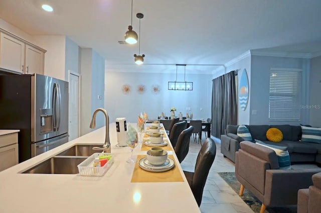 kitchen featuring hanging light fixtures, stainless steel refrigerator with ice dispenser, sink, and ornamental molding