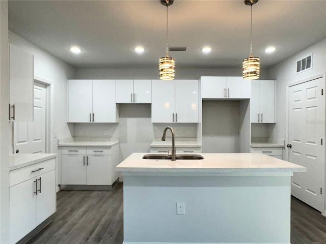 kitchen featuring decorative light fixtures, sink, a center island with sink, and white cabinets