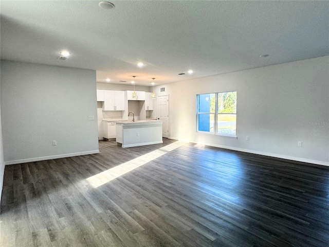 unfurnished living room with sink and dark wood-type flooring