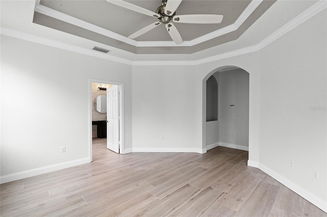 unfurnished room with a raised ceiling, ceiling fan, ornamental molding, and light hardwood / wood-style floors