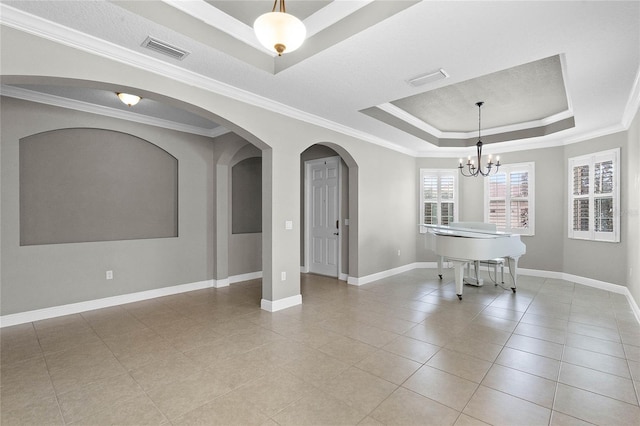 tiled spare room with crown molding, a tray ceiling, and a notable chandelier