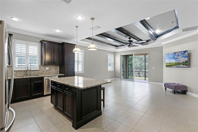 kitchen featuring pendant lighting, ornamental molding, stainless steel appliances, and a kitchen island