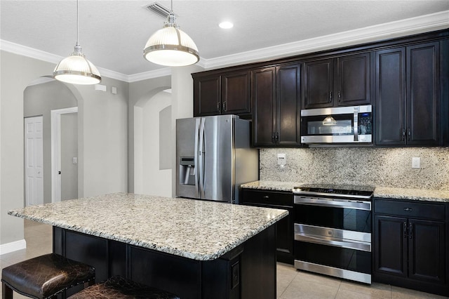 kitchen featuring tasteful backsplash, decorative light fixtures, stainless steel appliances, and a center island