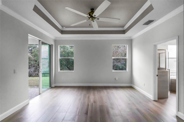 spare room featuring a raised ceiling, crown molding, ceiling fan, and light wood-type flooring