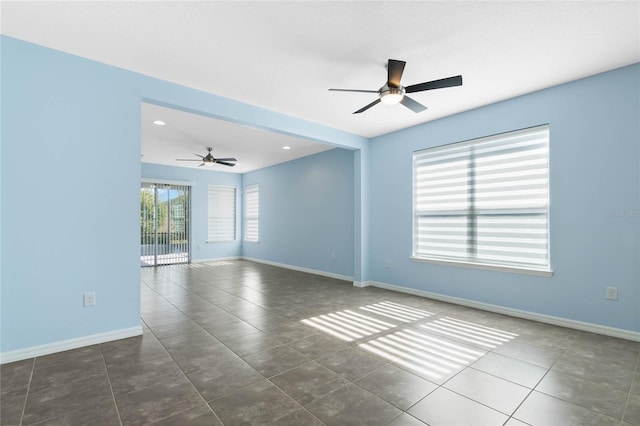 unfurnished room featuring dark tile patterned flooring and ceiling fan