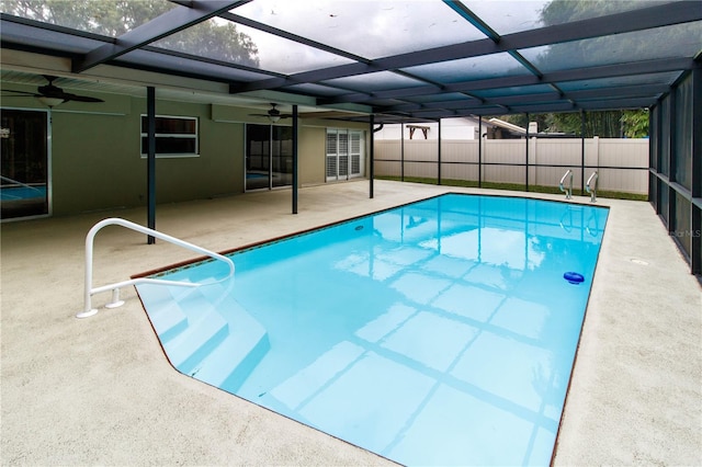 view of pool with a patio, ceiling fan, and glass enclosure