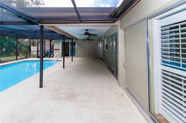 view of swimming pool with ceiling fan, glass enclosure, and a patio