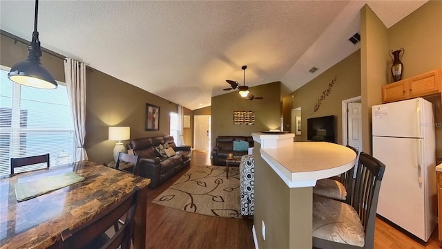 kitchen with lofted ceiling, hanging light fixtures, white fridge, and light wood-type flooring