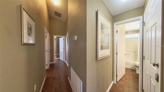 corridor with dark hardwood / wood-style flooring and a textured ceiling