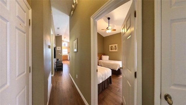 corridor featuring dark wood-type flooring and lofted ceiling