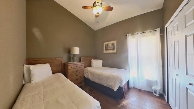 bedroom featuring vaulted ceiling, dark wood-type flooring, ceiling fan, and a closet