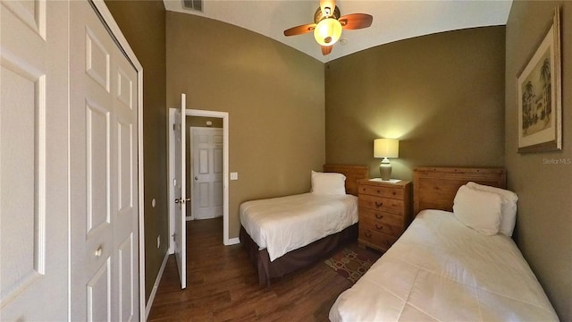 bedroom with vaulted ceiling, dark wood-type flooring, ceiling fan, and a closet