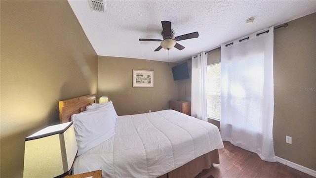 bedroom with dark hardwood / wood-style flooring, a textured ceiling, and ceiling fan