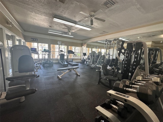 exercise room with ceiling fan and a textured ceiling