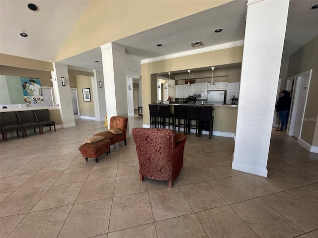 living room with light tile patterned floors, vaulted ceiling, a textured ceiling, and ornate columns