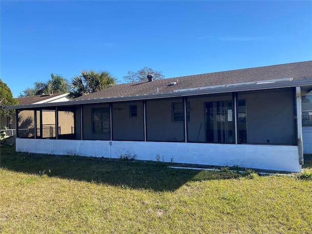 back of property with a sunroom and a lawn