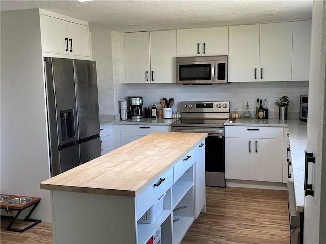 kitchen with stainless steel appliances, decorative backsplash, light wood-style flooring, and a center island