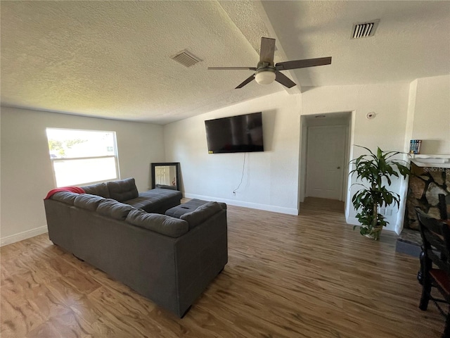 living area featuring visible vents, wood finished floors, and vaulted ceiling