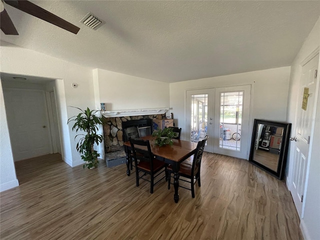 dining room featuring visible vents, a textured ceiling, wood finished floors, french doors, and ceiling fan