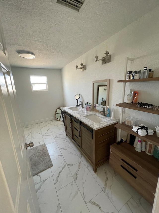 bathroom with a textured ceiling, visible vents, marble finish floor, and a sink